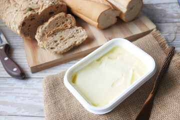cutting butter on chopping board and brown bread on background  - obrazy, fototapety, plakaty
