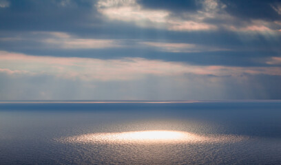 Beautiful landscape with rainbow and lightning over the calm sea at sunset 