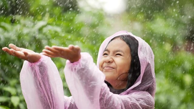 Happy girl wears raincoat and puts her hand
