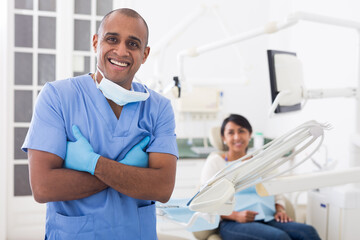 Obraz premium Portrait of positive dentist in dental office on the background of patient