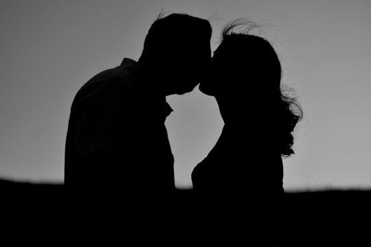 
Bride and groom kiss at sunset, photo against light.