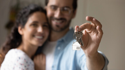 Close up focus on keys in hands of sincere smiling millennial couple, cheerful two young homeowners...
