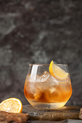 Glass of whiskey with lemon and ice on stone background.
