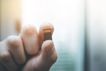 Young man is holding a tiny memory card in his hand, text space