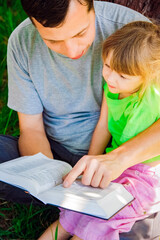 happy father with a child reading a book on the nature of the Bible