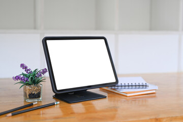 Fototapeta premium Digital tablet with blank screen, notebook and house plant on wooden desk.