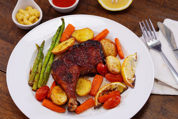 Homemade Baked Chicken Drumstick with Potatoes in a white plate on an old wooden table.