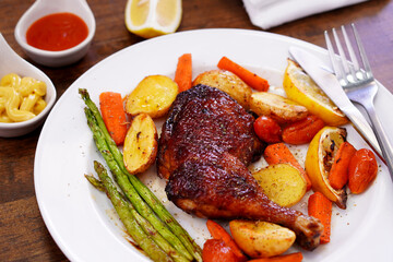 Homemade Baked Chicken Drumstick with Potatoes in a white plate on an old wooden table.