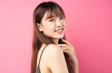 Portrait of a beautiful young asian girl posing on a pink background