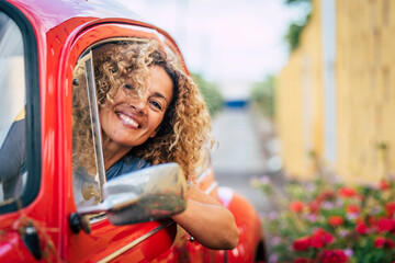 Portrait of cheerful happy adult pretty woman smile and enjoy driving car - caucasian female have fun outside the window of her vehicle - garden and road in background - people driving