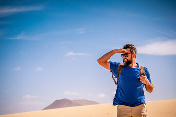 Adult man enjoy outdoor wild nature and adventure leisure activity alone walking inthe desert - mountains and blue sky in background - concept of freedom and exploration