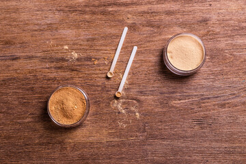 Mineral powder of different colors with a spoon dispenser for make-up on wooden background
