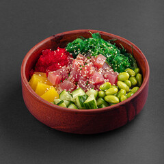 Hawaiian tuna poke bowl with vegetables on grey background