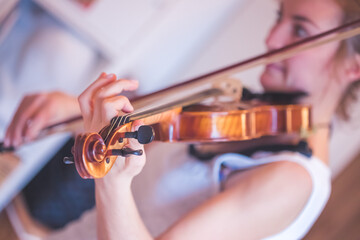 Practicing classical music and violin concept: Young girl happily plays on her violin