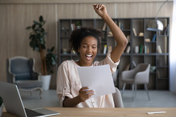 Overjoyed laughing young african american woman holding paper correspondence letter, celebrating getting good news, admission bank statement, dream job offer, loan approval, excellent test results.