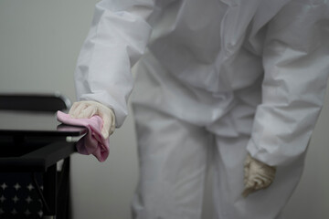 Worker in protective suit wiping table to prevent spread of coronavirus