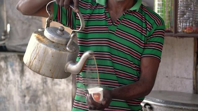 Men pouring hot tea, Indian chai from the street stall