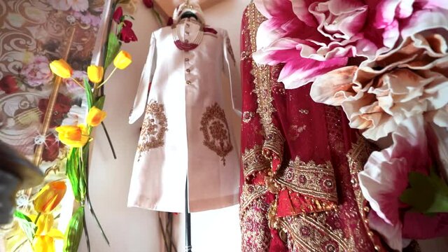 Indian Bride and Groom&rsquo;s wedding dress kept at display with beautiful flowers. Pan shot of Men&rsquo;s Royal sherwani and women&rsquo;s saree for Indian marriage. 


