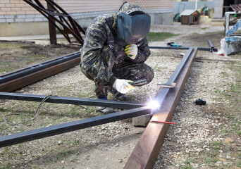 Workers weld metal for sliding gates.