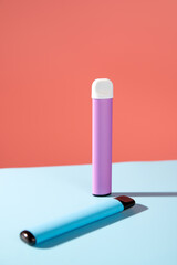 disposable electronic cigarettes with shadow on a pink and blue background with copy space. The concept of modern smoking, vaping and nicotine.