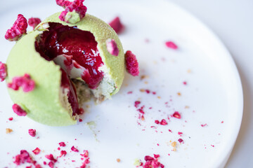Tasty pistachio - raspberry pie on a white plate.
