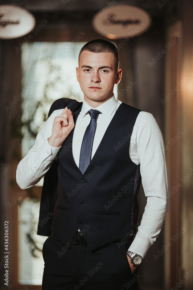 Wall mural vertical shot of a handsome bosnian caucasian man wearing a suit, posing indoors