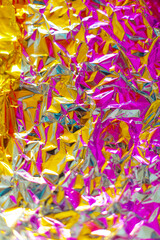 Yellow pink abstract chrome metallic background. Bold crumpled foil texture with gradient of magenta and warm yellow. Fusion futuristic fashion background. Good for party, rave, disco and young design