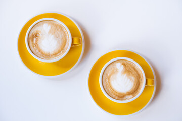 Yellow cups of delicious cappuccino on a white background.