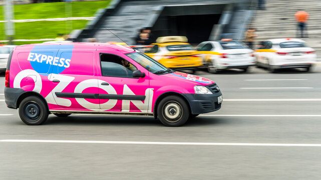 Delivery pink van of the Russian online store Ozon. Side view of car with Ozon logo. Courier rides on highway city road