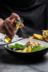 Healthy vegetable buddha bowl lunch with grilled chicken breast, halloumi, pineapple, avocado, green rocket salad, lime. addition of olive oil freezing in the air