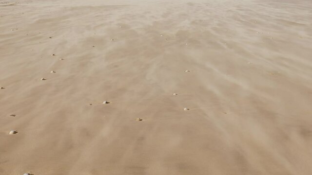 Closeup of fast-moving sand at the beach, heavy wind. Environmental background footage. Shot at 60fps.