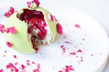Tasty pistachio - raspberry pie on a white plate.