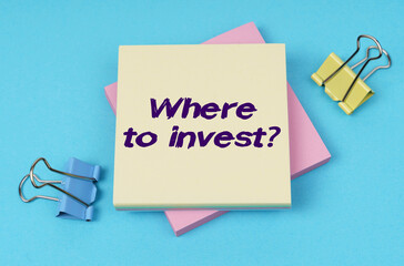 On the table are paper clips, note paper with text - Where to invest