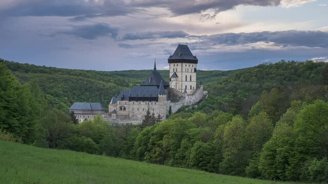View of medieval castle Karlstejn in the Czech Republic. Gothic casle surrounded by hills and forest during sunset. 4k time lapse video
