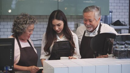 Asian senior man and woman teaching intern to be a barista of coffee cafe. Young girl training to make coffee to be a good barista. Concept of business, education, food and drink.
