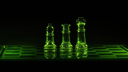 Piony szachowe szklane podświetlone na kolor zielony na czarnym tle - obrazy, fototapety, plakaty