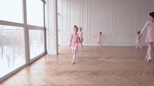 Girls dancers in ballet school learns to dance. Little Ballerinas in training in pink dancing suit. Children's ballet school. School of ballet.