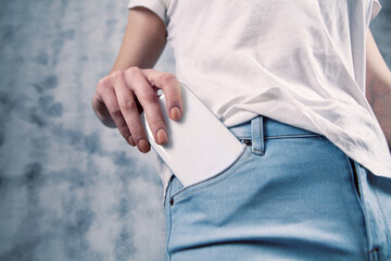 young girl puts the phone in her front pocket - obrazy, fototapety, plakaty