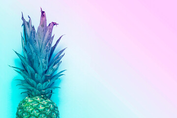 whole ripe pineapple on a blue background. Added color gradient. Top view, flat lay
