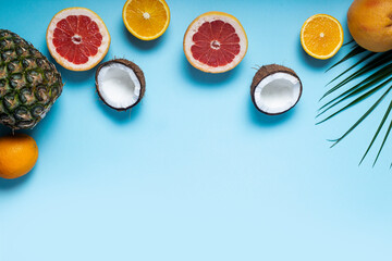exotic fruits on blue. Pineapple, coconut, orange, grapefruit. Top view, flat lay