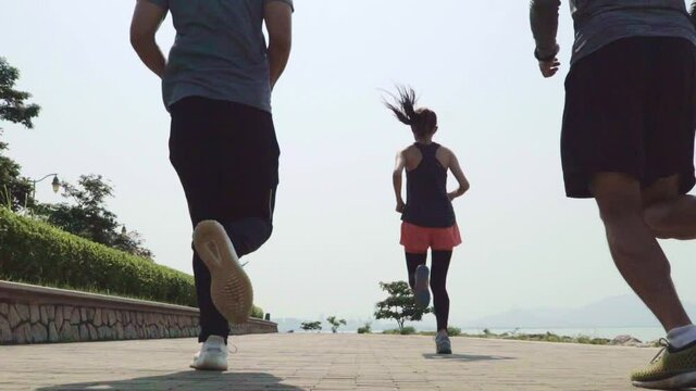 group of young asian athletes running training outdoors in seaside park
