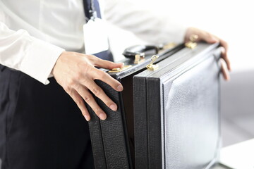 Close up of businessman holding briefcase in office