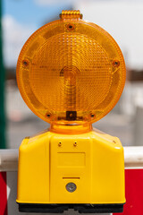Gelbe Baustellenlampe befestigt an einer Absperrung im Hochformat