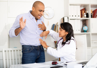 Obraz premium Qualified female doctor palpating abdomen of male patient complaining of pain in medical office