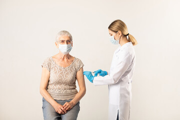 A doctor giving an injection of a covid-19 vaccine to an elderly patient.