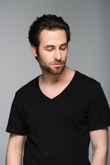 Obraz premium good-looking man in black t-shirt looking away while posing isolated on gray.