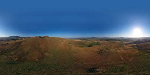 360 degree aerial photo of the wheat fields in the heart of Sicily in the Erei mountains. Sicilian wheat cultivation. Small rural villages of Ramacca and Raddusa. Hay and grain. Etna view.