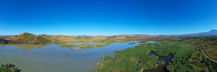 Fototapeta na wymiar 180 degrees aerial photo of the Oasis of Ponte Barca a protected area in the heart of Paternò in Sicily. Wetland that attracts numerous waterfowl. Nesting place of the Sultan chicken. Etna view.