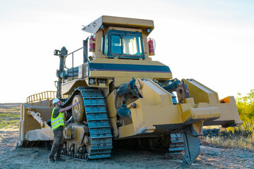construction worker checking excavator, heavy machinery. big truck used to make roads © Diego