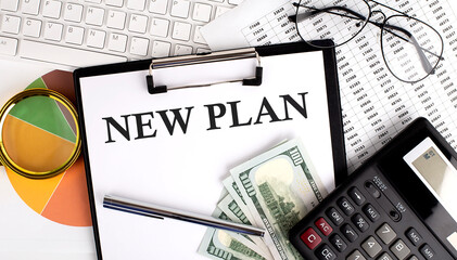 Text NEW PLAN on Office desk table with keyboard, dollars,calculator ,supplies,analysis chart on the white background.